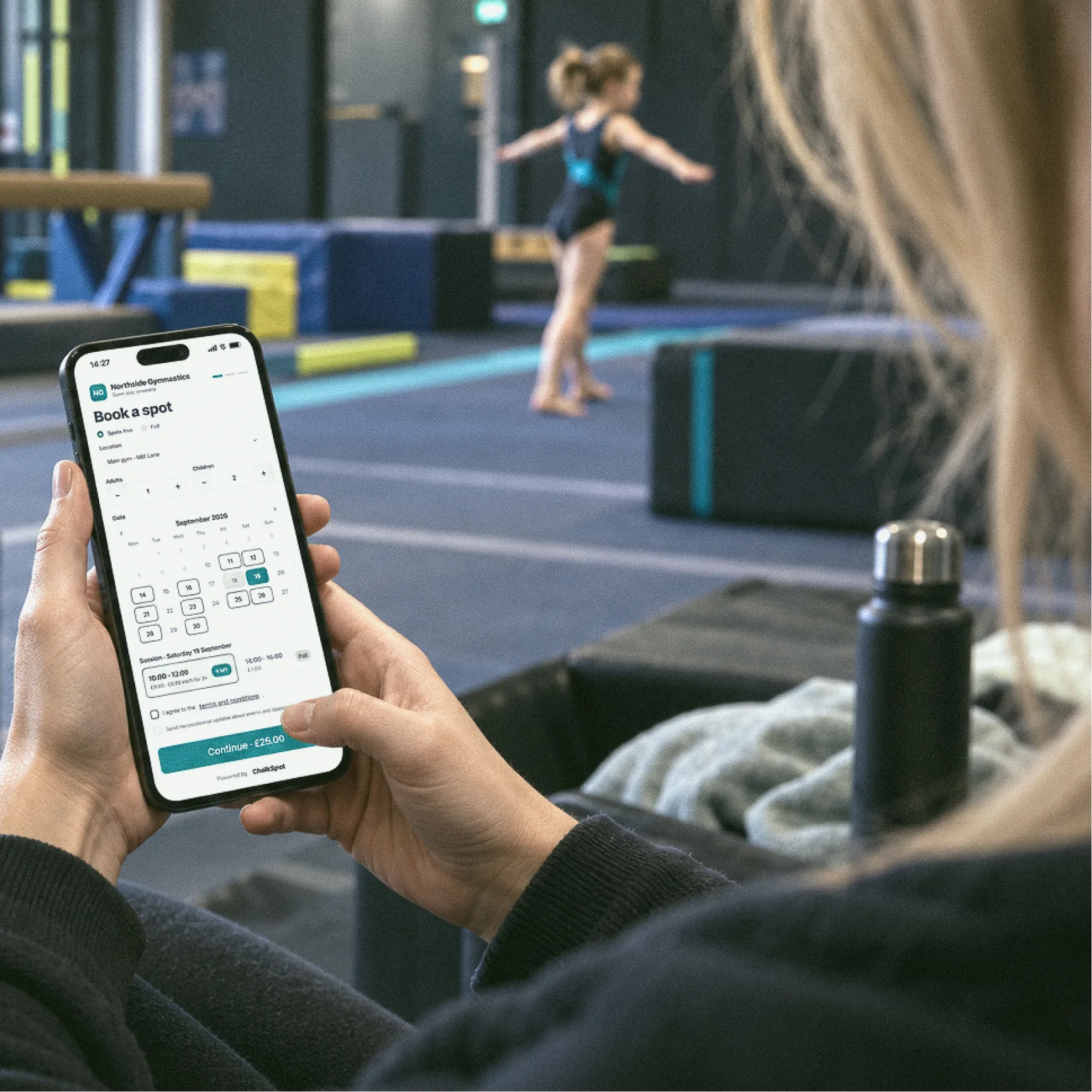 A parent booking a session on their phone at the gym